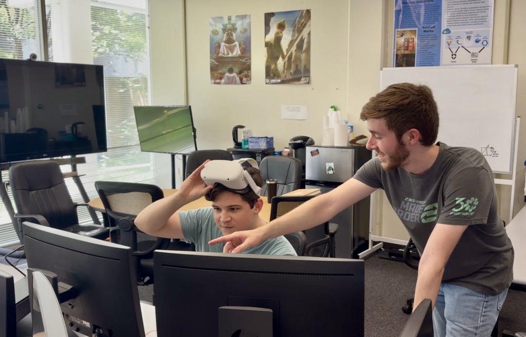 VRTEX tutor demonstrating a VR headset to a student in the lab